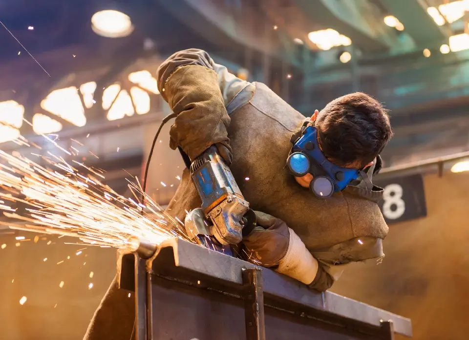 A man wearing protective gear while using an angle grinder.